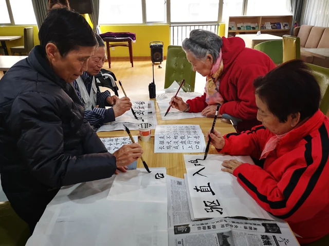 长者围桌练习毛笔书法